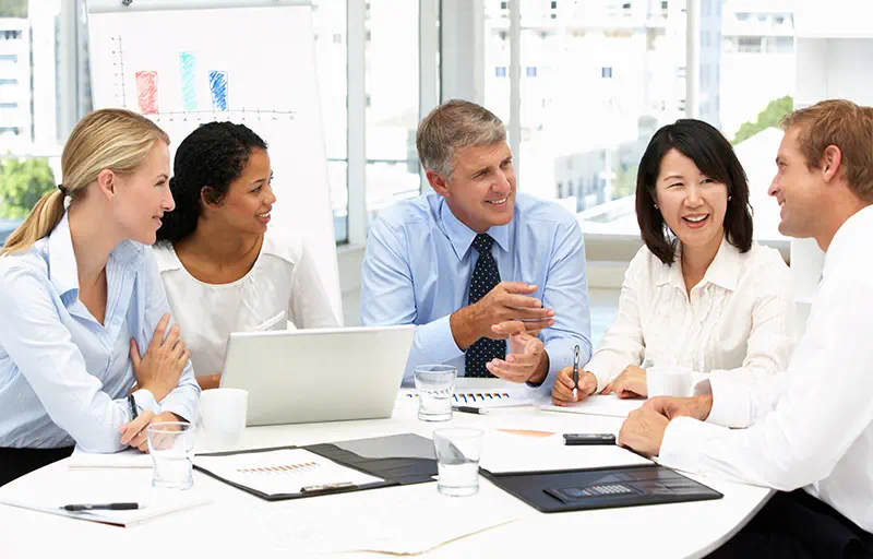 End-to-End Support A group of business people holding a discussion in a meeting room.