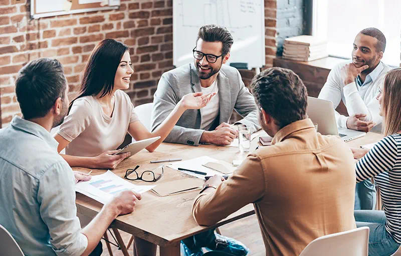 Tailored Solutions A group of business people discuss something in a meeting room.