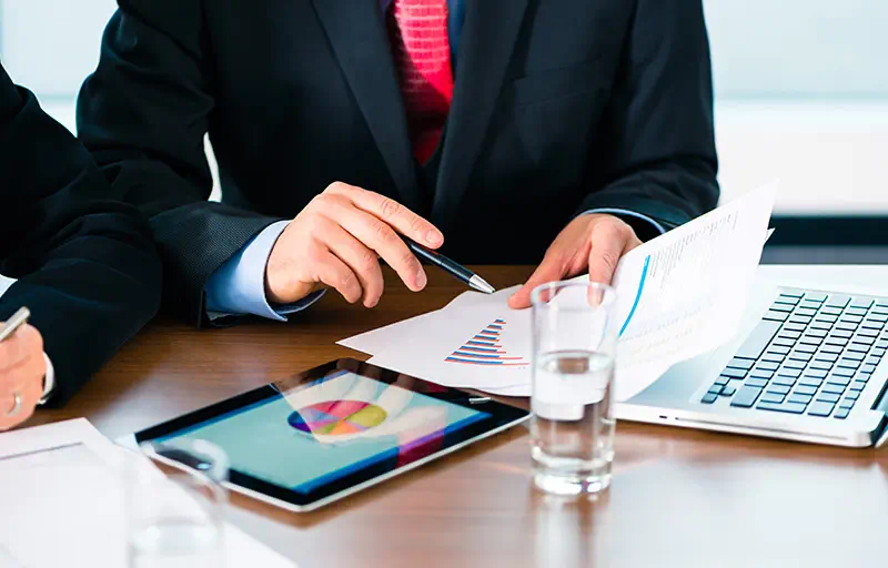 Buyer Screening Two business men looking through a report with charts and graphs.