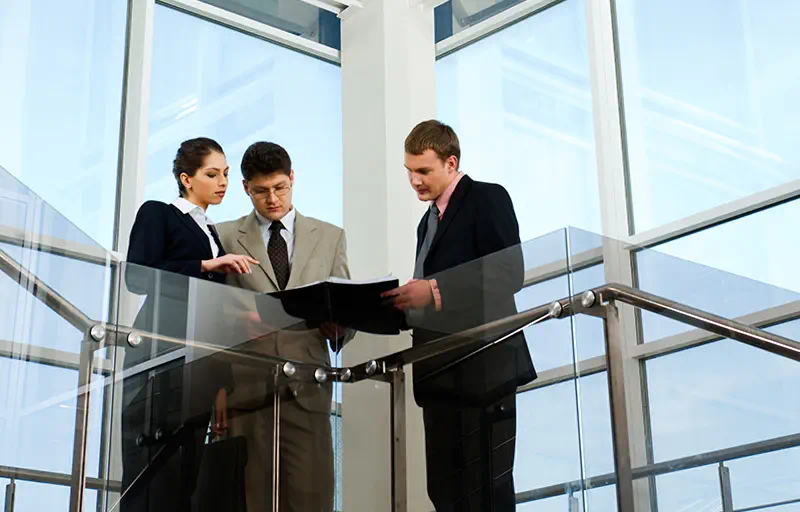 Property Evaluation Three people looking over notes in a modern office building.