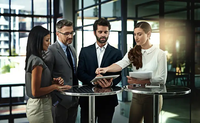 A group of business people meet in a standing meeting.