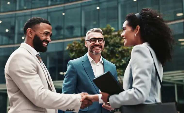 Three business people meet in front of a commercial building.